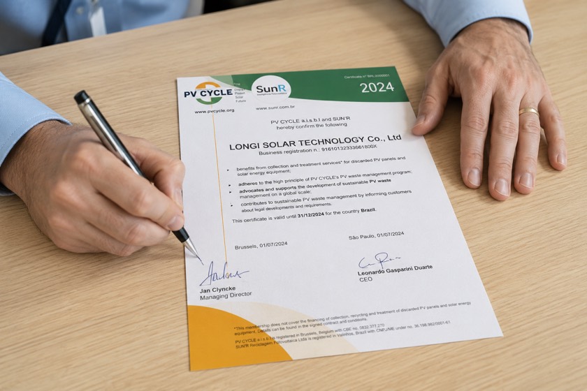 Mãos assinando certificado de reciclagem PV CYCLE e SunR sobre a mesa